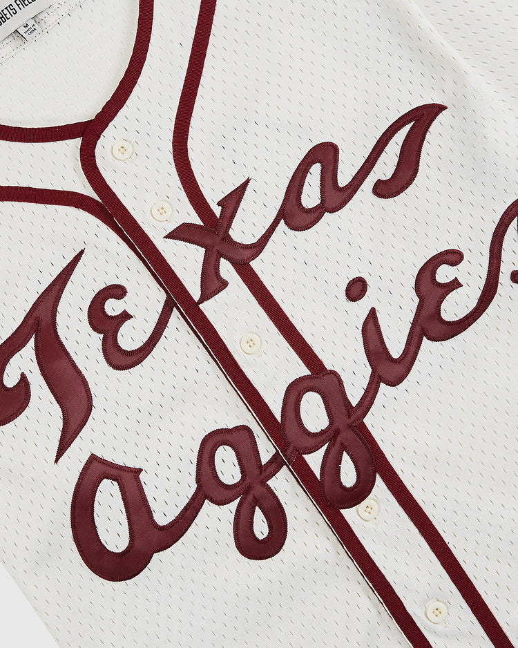 A close-up of the Ebbets Field Texas A&M University 1952 Button-Up Mesh Jersey, showcasing white mesh, maroon trim, and script Texas Aggies text inspired by the classic 1952 team uniform.
