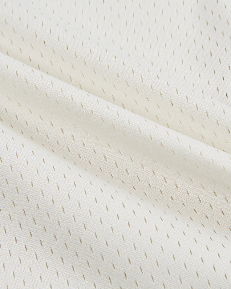 Close-up of the Ebbets Field Texas A&M University 1952 Button-Up Mesh Jersey, featuring white textured fabric with small, diagonal perforations—evoking a vintage baseball style—with gentle folds and soft shadows.