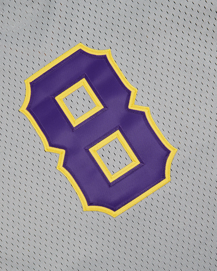 A large purple number 8 outlined in yellow is sewn onto a gray v-neck mesh jersey, inspired by the classic 1987 Louisianna State University jersey by Ebbets Field.