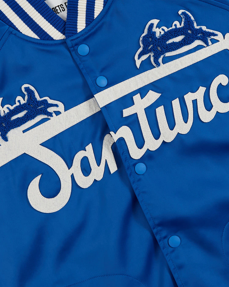 Close-up of the Ebbets Field Santurce Cangrejeros Cotton Lined Satin Varsity Jacket, featuring white buttons, blue-and-white striped collar, and large script with embroidered graphics honoring Puerto Rican baseball legends.