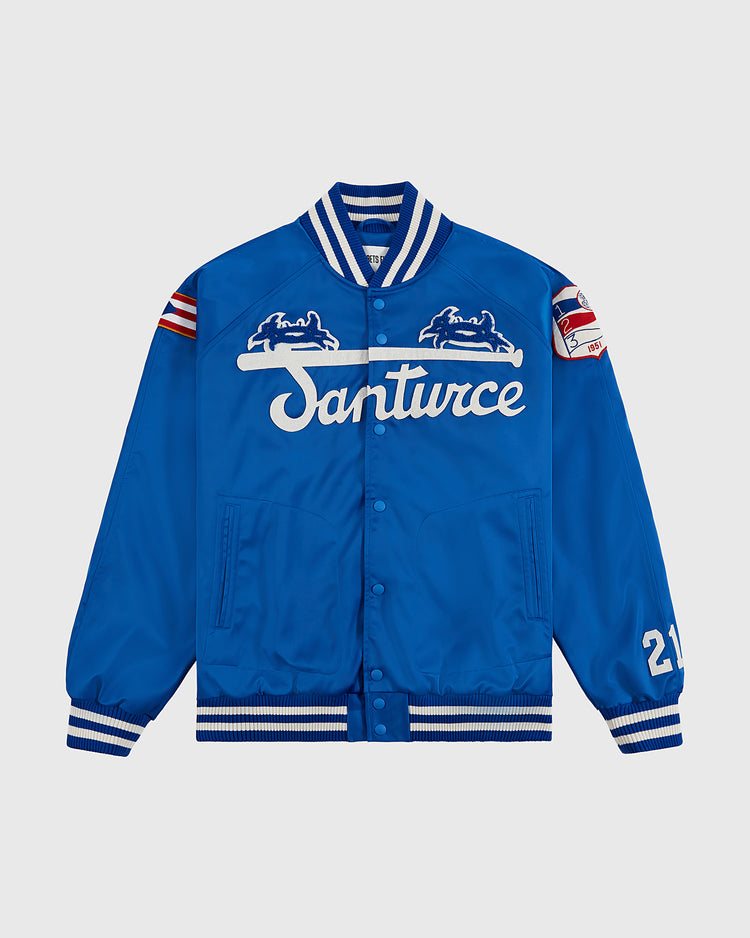The Ebbets Field Santurce Cangrejeros Cotton Lined Satin Varsity Jacket is blue with white team lettering, chest embroidery, striped ribbed cuffs and collar, a 21 patch on one sleeve, and a Puerto Rican baseball flag patch on the other.