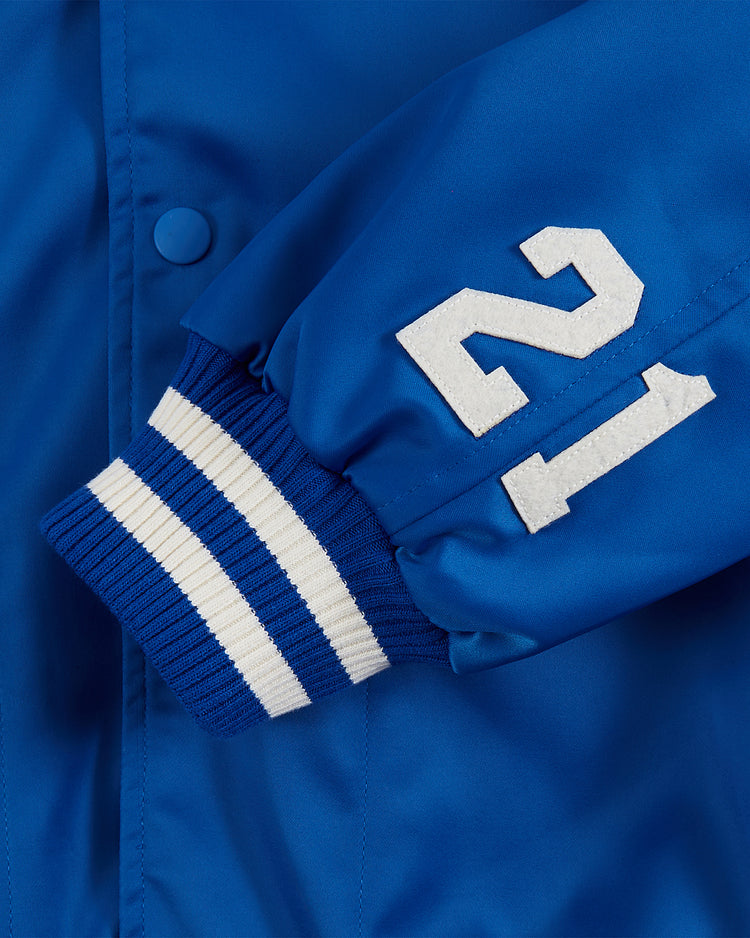 Close-up of the Santurce Cangrejeros Cotton Lined Satin Varsity Jacket by Ebbets Field, featuring a blue vintage sleeve with white striped ribbed cuff and white felt number 21, inspired by Puerto Rican baseball legends.