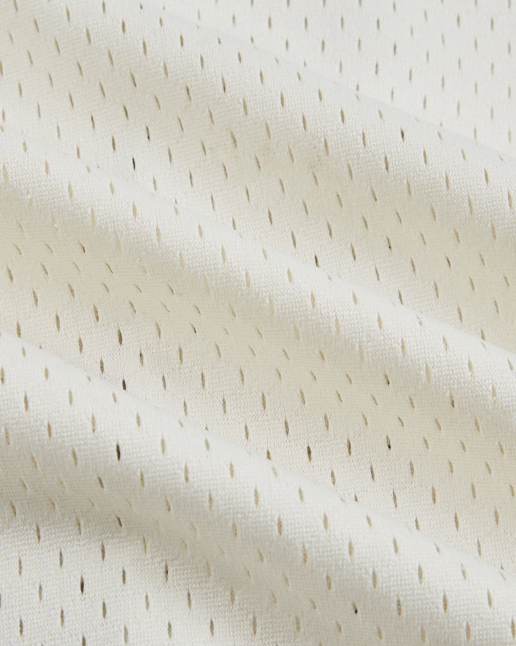 Close-up of the Ebbets Field Jackie Robinson Comic Book Hero Button-Up Mesh Jersey, featuring off-white mesh fabric with small, evenly spaced holes and soft folds that recall classic baseball style.