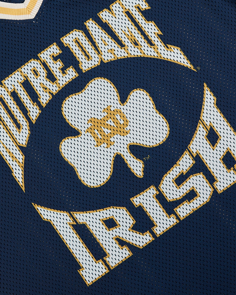 Close-up of the Ebbets Field University of Notre Dame V-Neck Mesh Jersey, showcasing gold and white lettering, a bold central shamrock, and classic mesh fabric for timeless Notre Dame spirit.