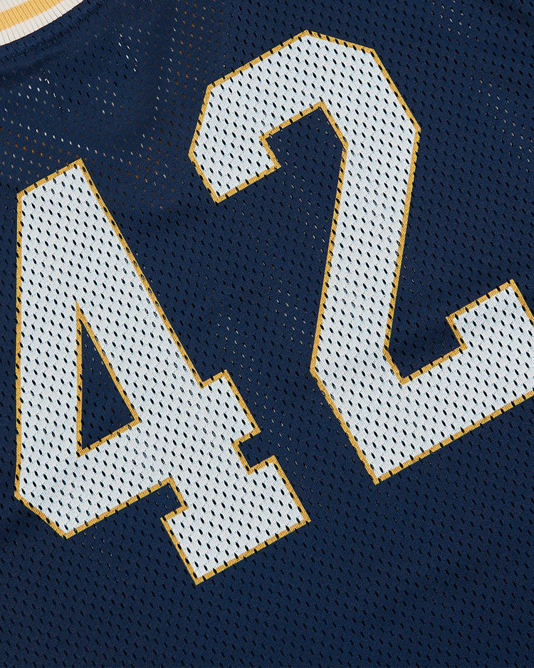 A close-up of the Ebbets Field University of Notre Dame V-Neck Mesh Jersey in navy blue, featuring large white number 42 outlined in gold, showcases classic vintage Notre Dame apparel style.