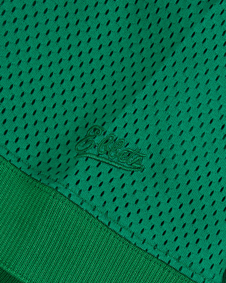 Close-up of the Ebbets Field University of Notre Dame V-Neck Mesh Jersey: green mesh fabric with black ventilation holes, ribbed trim, and subtle stitched 