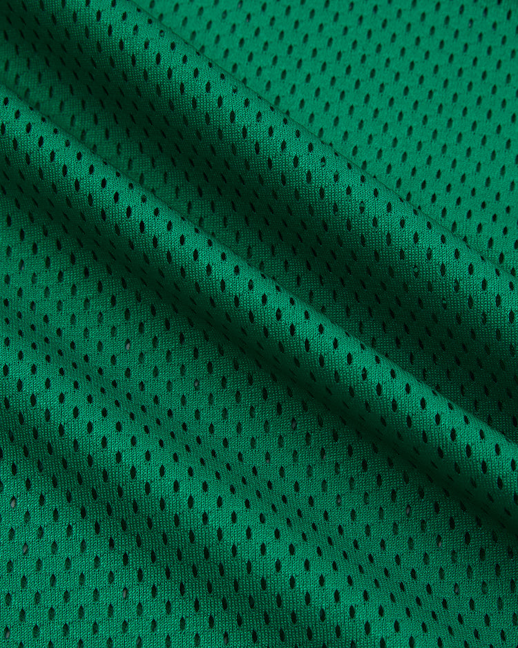 Close-up of the Ebbets Field University of Notre Dame V-Neck Mesh Jersey shows textured green fabric with small, evenly spaced holes and vintage-inspired folds for a classic baseball look.