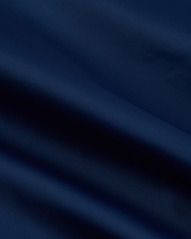 A close-up of smooth, dark blue fabric with gentle folds and soft shadows highlights the texture and sheen of the Ebbets Field Jackie Robinson Comic Book Hero Cotton Lined Satin Varsity Jacket.