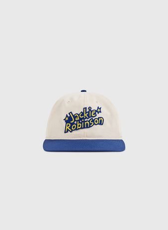 The Ebbets Field Jackie Robinson Comic Book Hero Cotton Twill Ballcap is white with a blue brim, and features his name in bold yellow letters outlined in blue, plus star accents around the text.