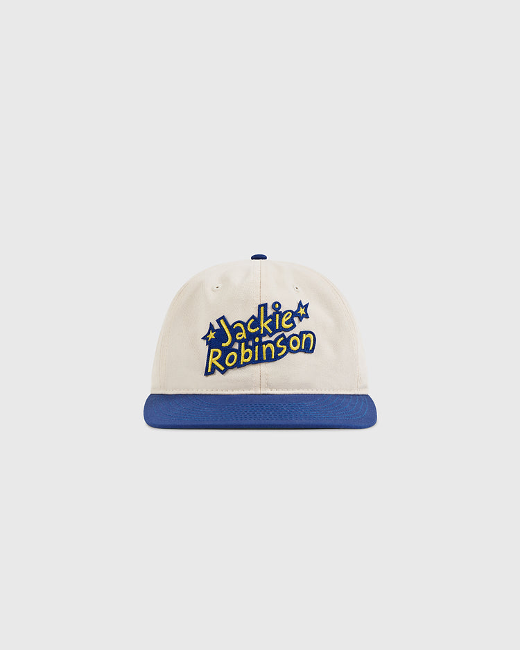 The Ebbets Field Jackie Robinson Comic Book Hero Cotton Twill Ballcap is white with a blue brim, and features his name in bold yellow letters outlined in blue, plus star accents around the text.