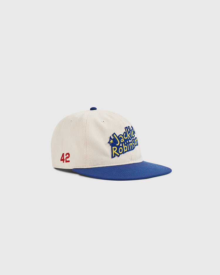 The Ebbets Field Jackie Robinson Comic Book Hero Cotton Twill Ballcap features a cream body, blue brim, “Jackie Robinson” embroidered in blue and yellow on front, and the number 42 in red on the side.