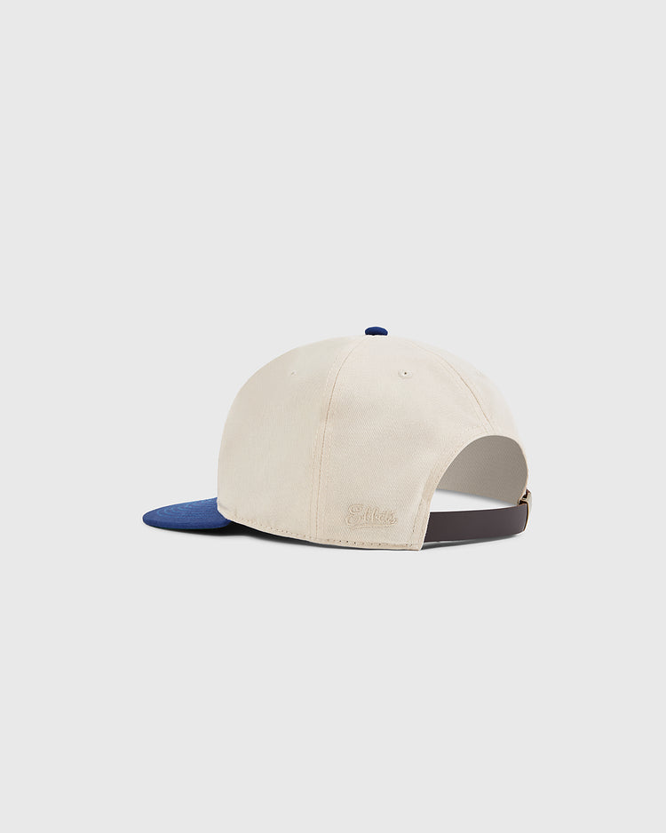 The Ebbets Field Jackie Robinson Comic Book Hero Cotton Twill Ballcap is cream-colored with a blue brim, an adjustable brown strap, and a small embroidered logo at the back, inspired by Jackie Robinson's iconic cap.
