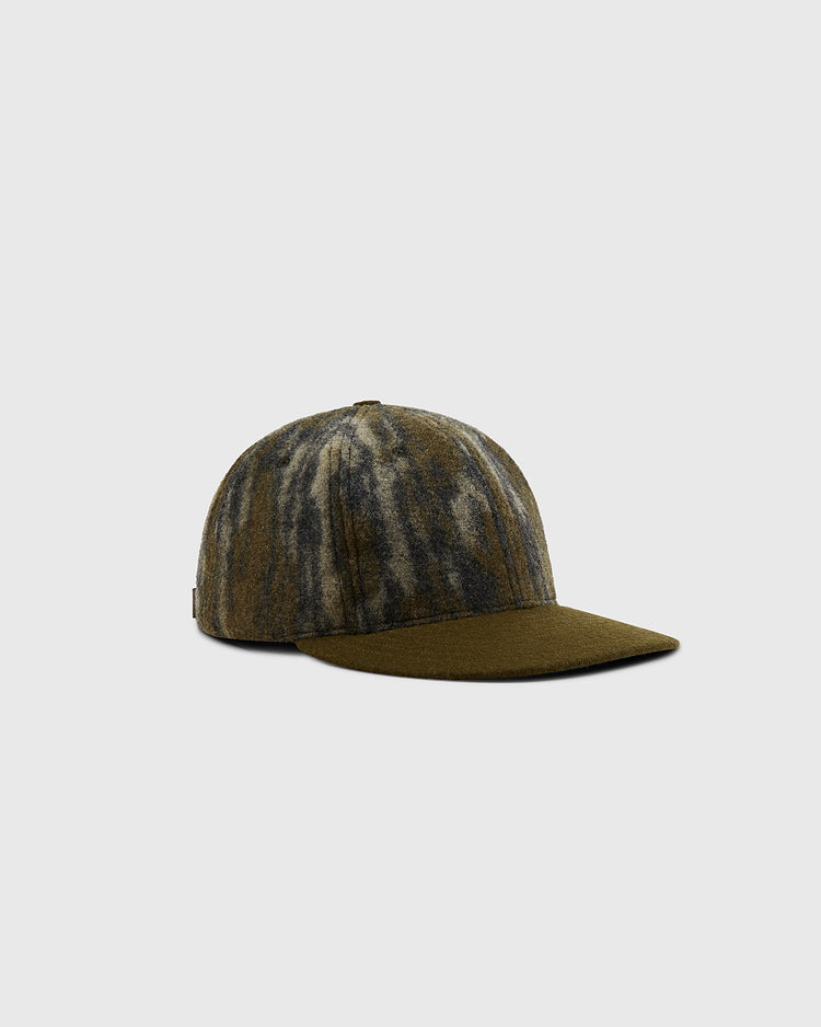 The Ebbets Field Mossy Oak x Ebbets Field Blank Ballcap features a marbled olive green and gray tie-dye effect, flat brim, and structured crown, shown against a light gray background.