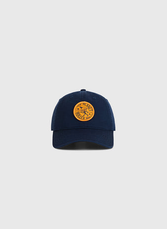 The Ebbets Field Chicago New Planet Roller Rink Washed Cotton Ballcap in navy features a round yellow patch with retro roller rink-inspired graphic and text, shown on a plain light gray background.