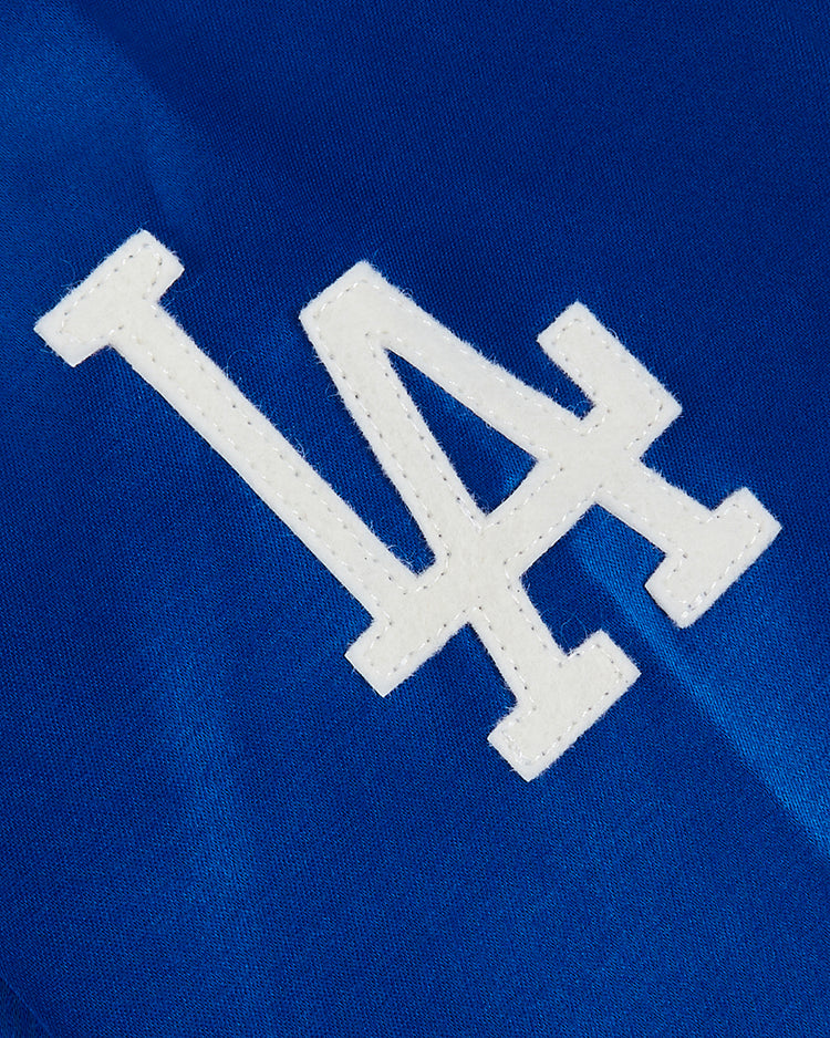 White LA letters in bold, stitched font on blue satin, inspired by the Los Angeles Dodgers 1962 Satin Windbreaker Jacket from EFF, reminiscent of what was worn on-field at Dodger Stadium.
