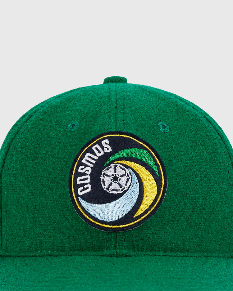 The Ebbets Field New York Cosmos Wool Ballcap features the classic team logo—a black, yellow, and green swirl with a soccer ball and COSMOS text—ideal for fans of Pelé and vintage soccer style.