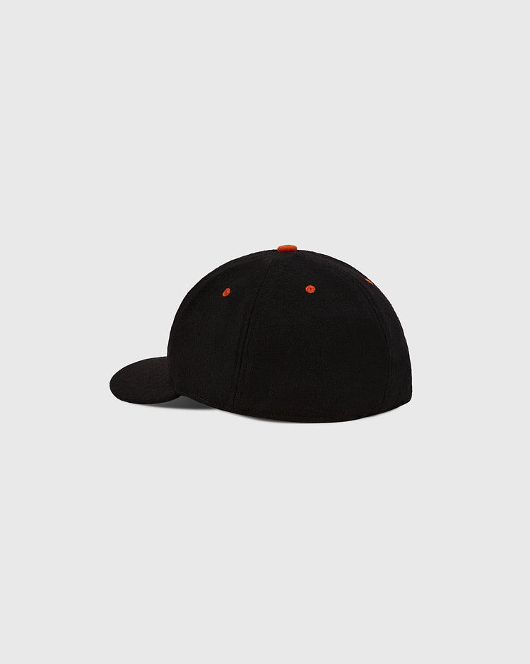 The Ebbets Field Los Angeles Aztecs Wool Ballcap, black with orange stitching and eyelets, is displayed from the back and slightly to the side against a plain light grey background.
