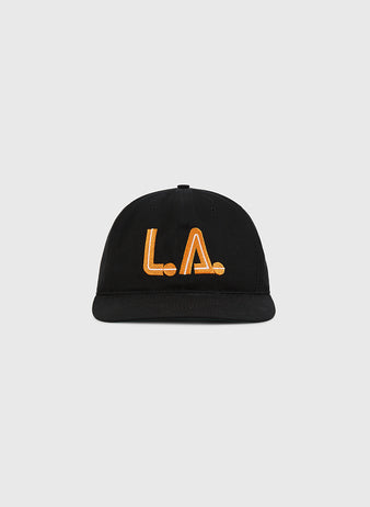 The Ebbets Field Los Angeles Aztecs Cotton Twill Ballcap in black features bold orange L.A. embroidery on the front, inspired by the historic NASL team, and is shown against a plain light gray background.