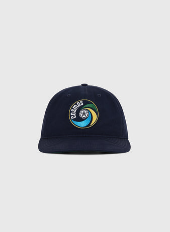 The Ebbets Field New York Cosmos Cotton Twill Ballcap in navy blue features an embroidered Cosmos logo with a stylized globe and colorful swoosh on the front, shown against a plain light gray background.