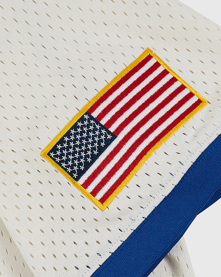 A close-up of the Pennsylvania Stoners Mesh Soccer Jersey by Ebbets Field shows its white mesh, blue trim, and the team’s yellow-bordered upside-down American flag patch—details honoring the ASL champions’ unique style.