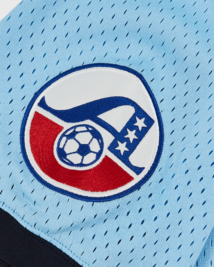A close-up of the Ebbets Field Chicago Cats Mesh Soccer Jersey shows a stitched patch with a stylized A, soccer ball, stars, and red and white details in a circular design, evoking classic American Soccer League style.