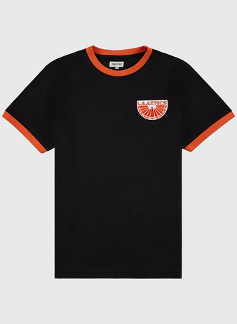 The Ebbets Field Los Angeles Aztecs Mesh Soccer Jersey is a black short-sleeve mesh top with orange trim on the collar and cuffs, and features an orange and red patch logo on the left chest, laid flat on a white background.
