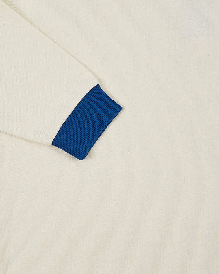 A close-up of the Ebbets Field Pennsylvania Stoner Vintage Soccer Goalie Jersey shows its cream color, collared design, blue ribbed sleeve cuff, and long sleeves, laid on a plain background.
