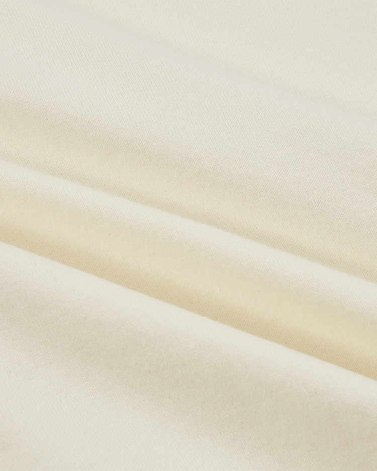 Close-up of smooth, cream-colored fabric with soft folds and subtle texture, evoking the Ebbets Field Pennsylvania Stoner Vintage Soccer Goalie Jersey, as gentle shadows highlight the vintage-inspired draping.
