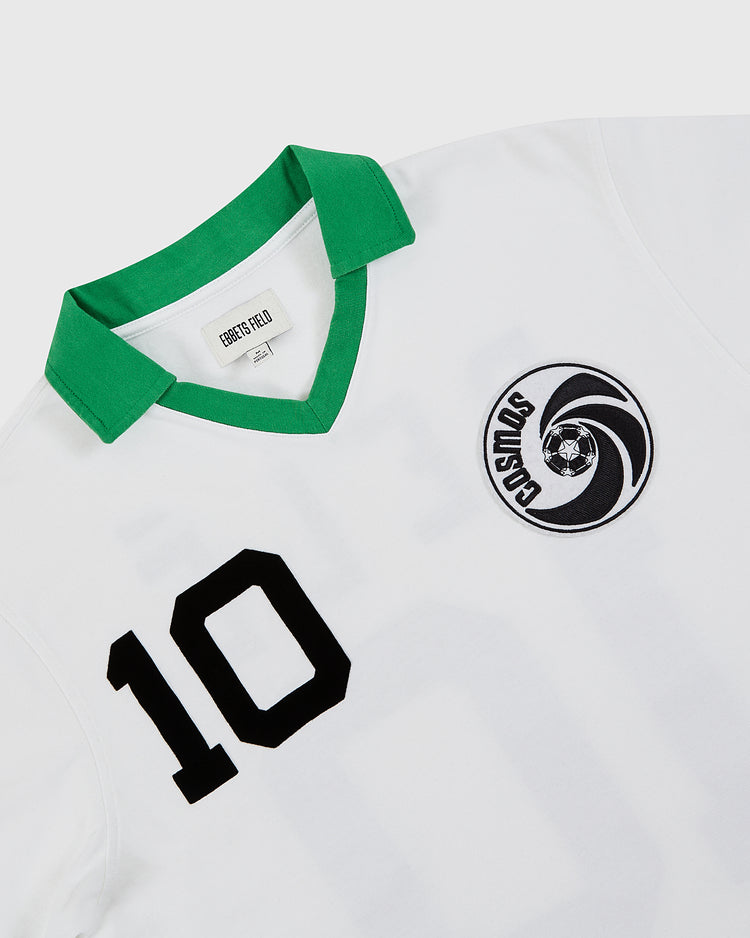 The Ebbets Field New York Cosmos Vintage Collar Soccer Jersey is a white cotton top inspired by Pelé, featuring a green collar, bold black 10, the classic circular Cosmos logo with soccer ball, and an inside label reading DESERT FIELD.