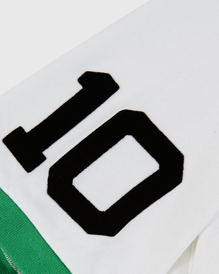 A close-up of the Ebbets Field New York Cosmos Vintage Collar Soccer Jersey in white cotton features a bold black number 10 and a green section inspired by the classic Pelé design visible underneath.