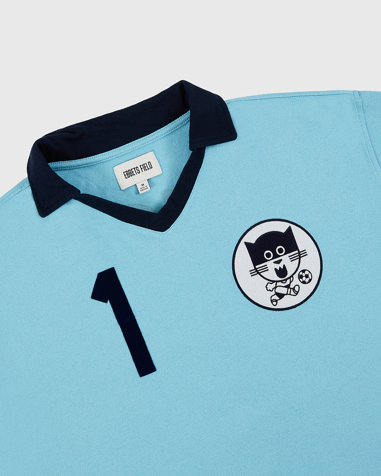 The Ebbets Field Chicago Cats Vintage Soccer Goalie Jersey features light blue long sleeves, a dark blue collar, a large front number 1, and a circular patch with a cartoon cat playing soccer, inspired by the classic goalie jersey.