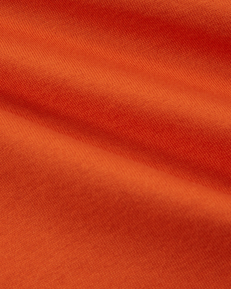 Close-up of the soft, textured orange fabric with gentle folds and shadows, evoking the smoothness and warmth of the Ebbets Field Los Angeles Aztecs Vintage Soccer Goalie Jersey.