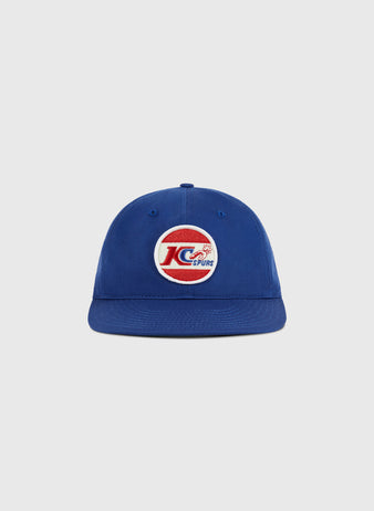 The Ebbets Field Kansas City Spurs Cotton Twill Ballcap is a blue flat-brim cap featuring a circular front patch with a red, white, and blue design inspired by the team’s NASL championship legacy.