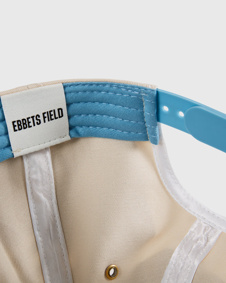 Close-up of the Dallas Tornados A-Frame Cotton Twill Ballcap by Ebbets Field, showing its beige and blue interior, a white brand label, and blue adjustable strap—a retro nod to NASL championship history.