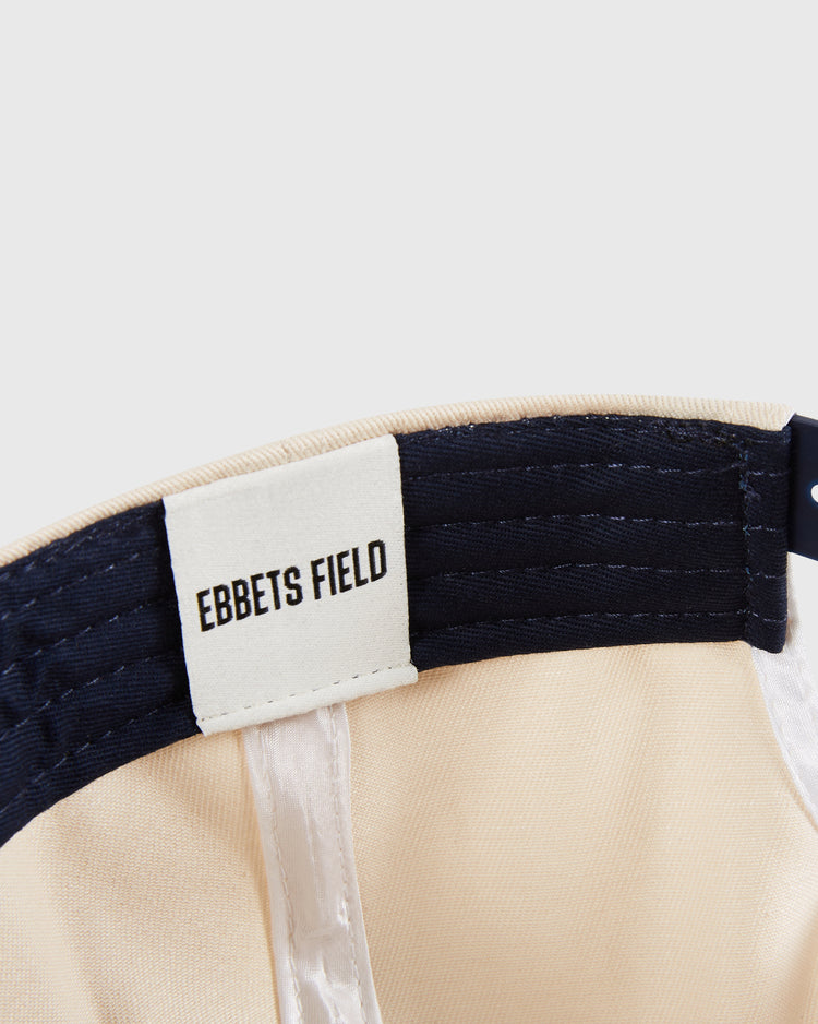 Close-up of the inside of a beige and navy New Jersey Americans A-Frame Cotton Twill Ballcap, featuring a white Ebbets Field label with black text stitched onto the inner band.
