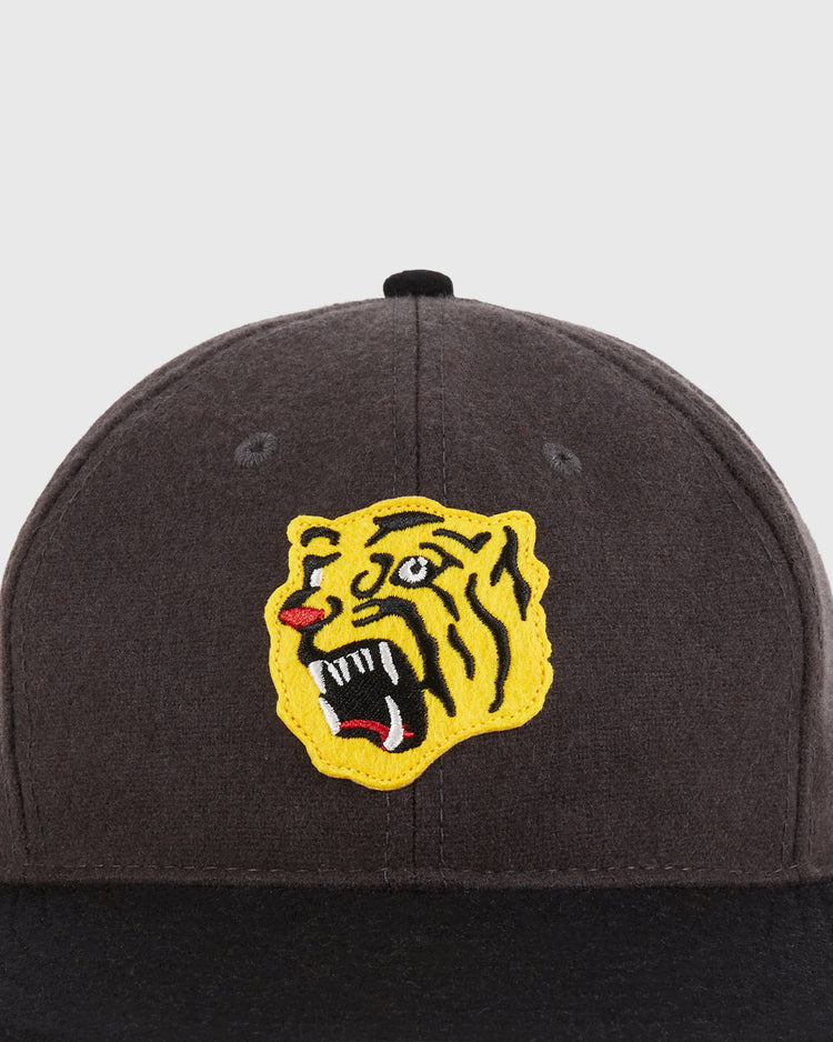 A close-up of the Ebbets Field Osaka Tigers 1940 Wool Ballcap, featuring a yellow embroidered roaring tiger head patch with red, white, and black details on the dark wool front.