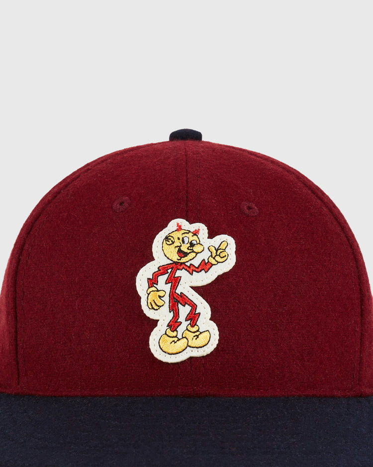 The Ebbets Field Reddy Kilowatt 1940 Wool Ballcap for kids is a maroon and navy cap with an embroidered patch of the cartoon character Reddy Kilowatt on the front.