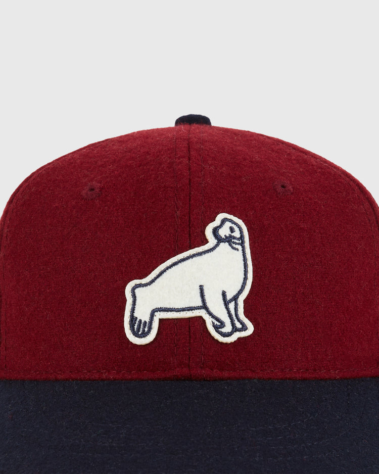 A close-up of the Ebbets Field San Francisco Seals 1940 Wool Ballcap (Youth Size) in red and navy, featuring a white embroidered seal with a navy outline on the front.
