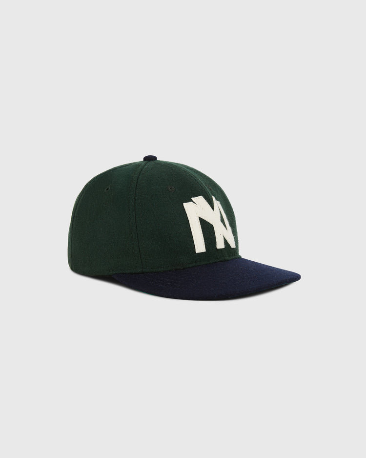 The Ebbets Field Brooklyn Eagles 1935 Wool Ballcap in youth size features dark green wool, a navy blue brim, and bold white NY letters, inspired by classic Negro Leagues hats, shown on a plain light gray background.