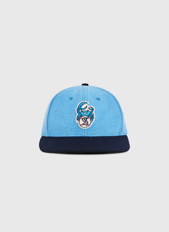 The Ebbets Field Santurce Cangrejeros Crab Wool Ballcap features light blue wool, a navy brim, and an embroidered blue crab with a baseball—honoring Puerto Rican baseball. Shown on a simple light background.