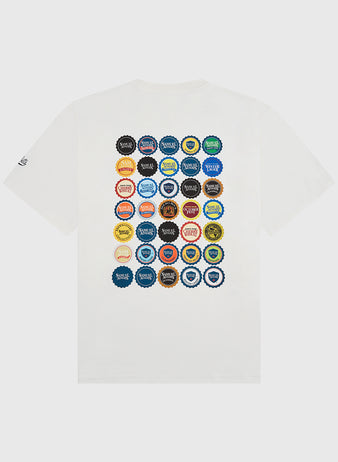 The Sam Adams Bottle Cap Short Sleeve Graphic T-Shirt by Ebbets Field features a grid of 36 colorful, unique bottle caps on the back—each with different logos and text—from their exclusive collaboration collection.