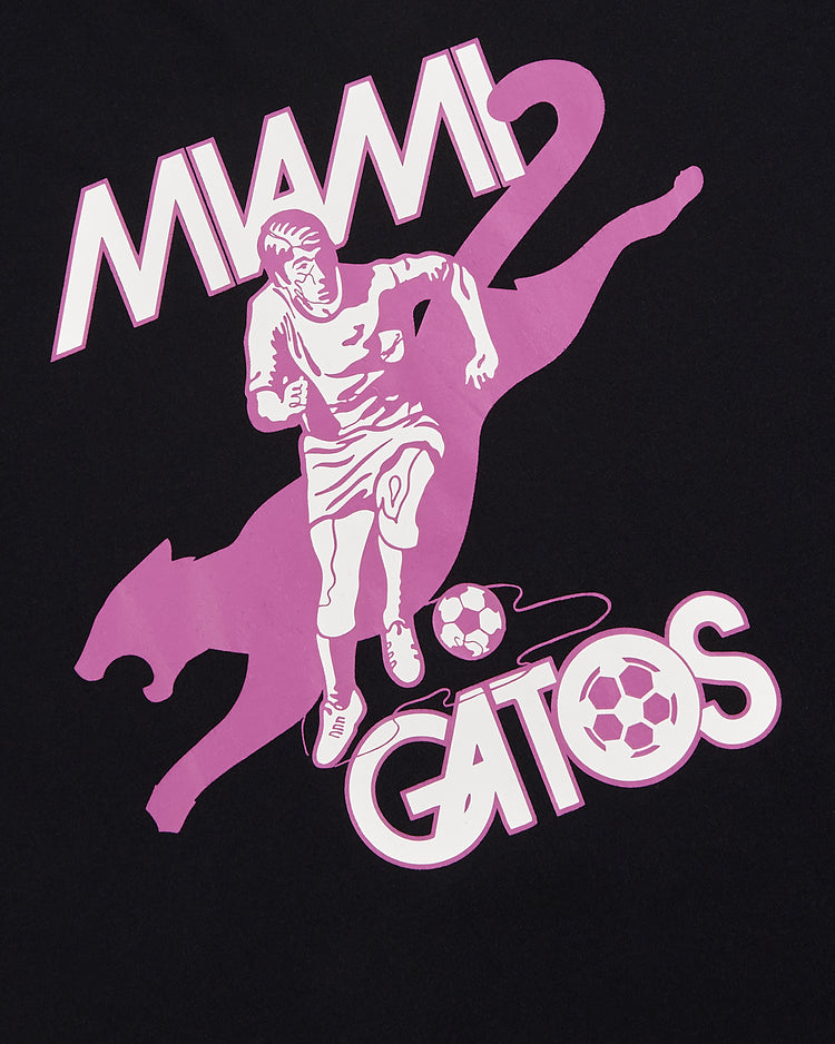 The Ebbets Field Miami Gatos Short Sleeve Graphic T-Shirt showcases a vintage soccer player, a large pink panther, and 