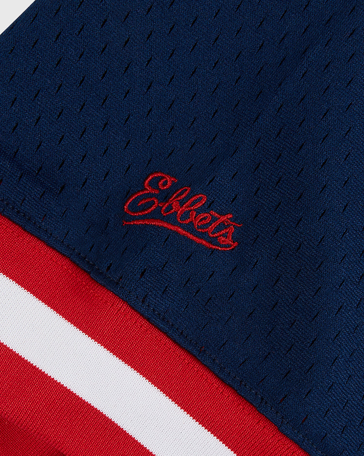 Close-up of the dark blue Sam Adams Mesh V-Neck Jersey by Ebbets Field, featuring red and white edge stripes and 