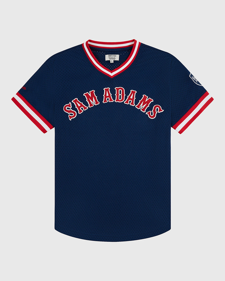 The Sam Adams Mesh V-Neck Jersey by Ebbets Field features navy blue vintage mesh, bold white and red SAM ADAMS lettering, striped cuffs and collar, and a small patch on the left sleeve.