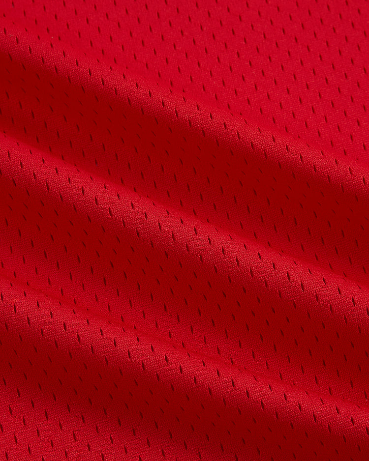 Close-up of vibrant red mesh fabric with small, evenly spaced perforations and soft diagonal folds, evocative of the material featured in the Ebbets Field Hilldale Athletic Club 1924 V-Neck Mesh Jersey.