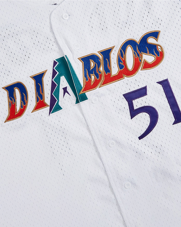 The Ebbets Field Randy Johnson El Paso Diablos Button Up Mesh Jersey features white mesh fabric with vibrant “DIABLOS” lettering across the front, highlighted by a green and purple “A” shaped like a mountain as an homage to El Paso Diablos style. The jersey also sports the number 51 in purple on the right, inspired by Randy Johnson’s classic uniform, while red and blue flame-like accents outline the letters for a bold finish.