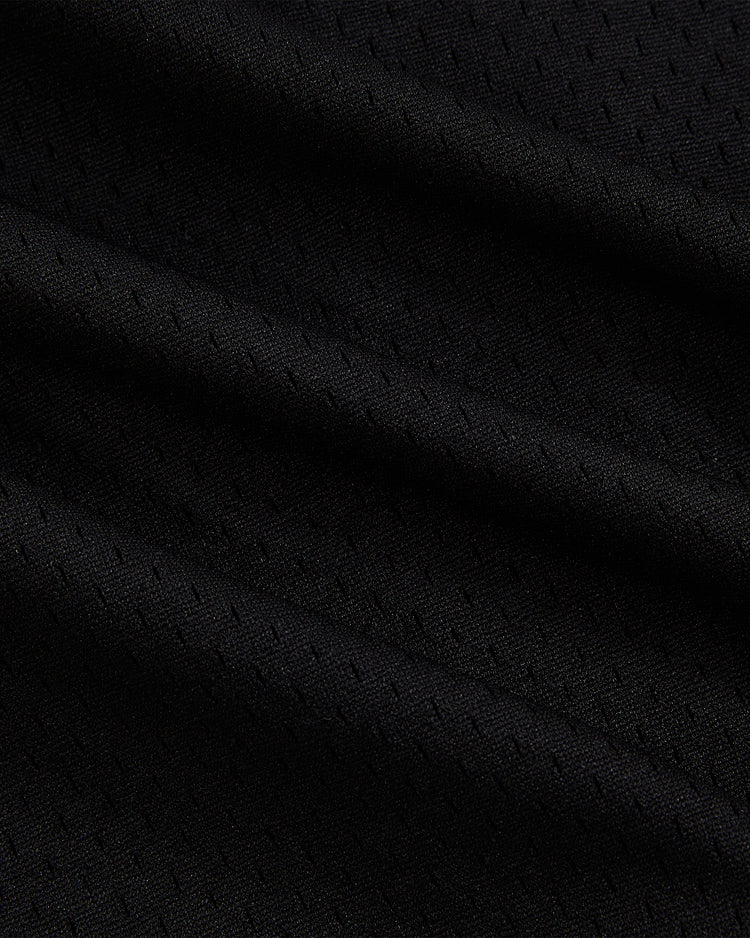 Close-up of black mesh fabric with subtle diagonal ridges and fine perforations, showcasing the detailed craftsmanship characteristic of the Ebbets Field Randy Johnson Tucson Sidewinders Button Up Mesh Jersey, which adds pattern and depth to the material.