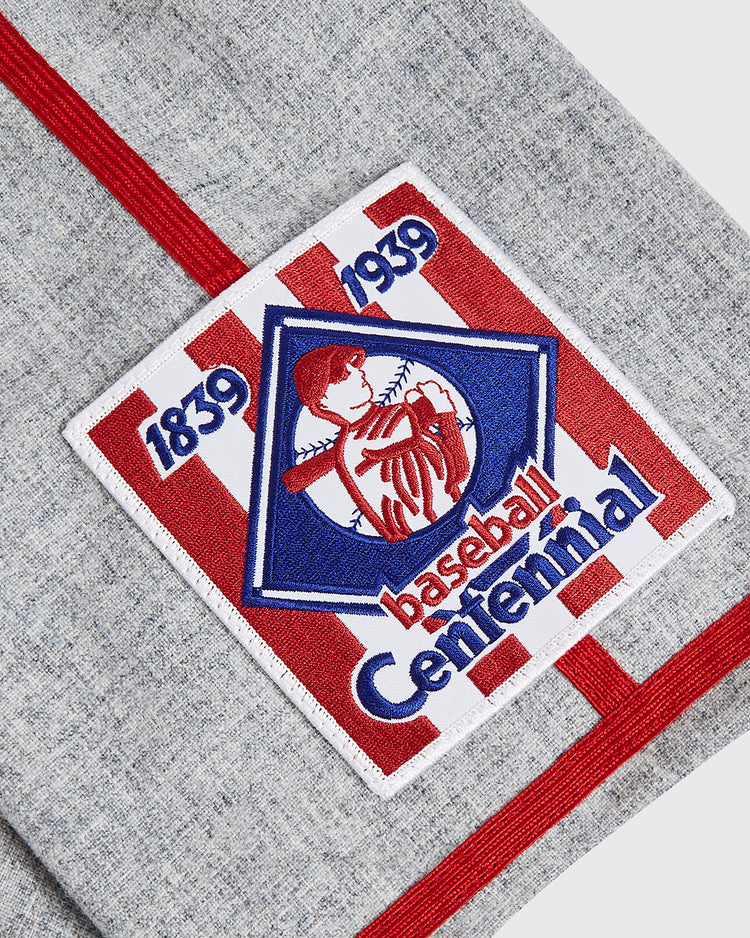 A fabric patch with red stripes features a baseball player and the words “1839 1939 baseball Centennial” on a gray textile background, evoking the classic style of the Ebbets Field Philadelphia Stars 1939 Wool Authentic Road Jersey.