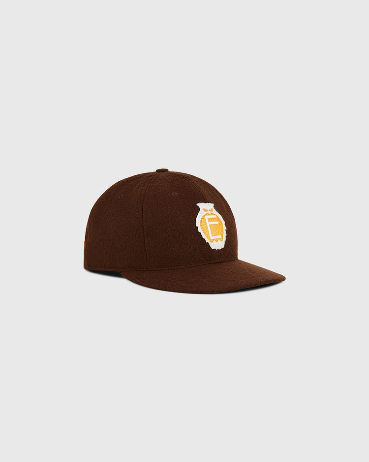 The Tecolotes 1935 Authentic Wool Ballcap by Ebbets Field is a brown baseball cap with a flat brim, featuring a yellow and white embroidered logo on the front, displayed on a plain light gray background.