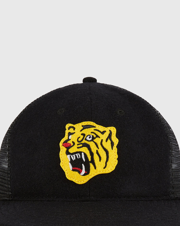 The Osaka Tigers Wool Mesh Trucker Ballcap by Ebbets Field features a black mesh design with an embroidered yellow roaring tiger head patch on the front.